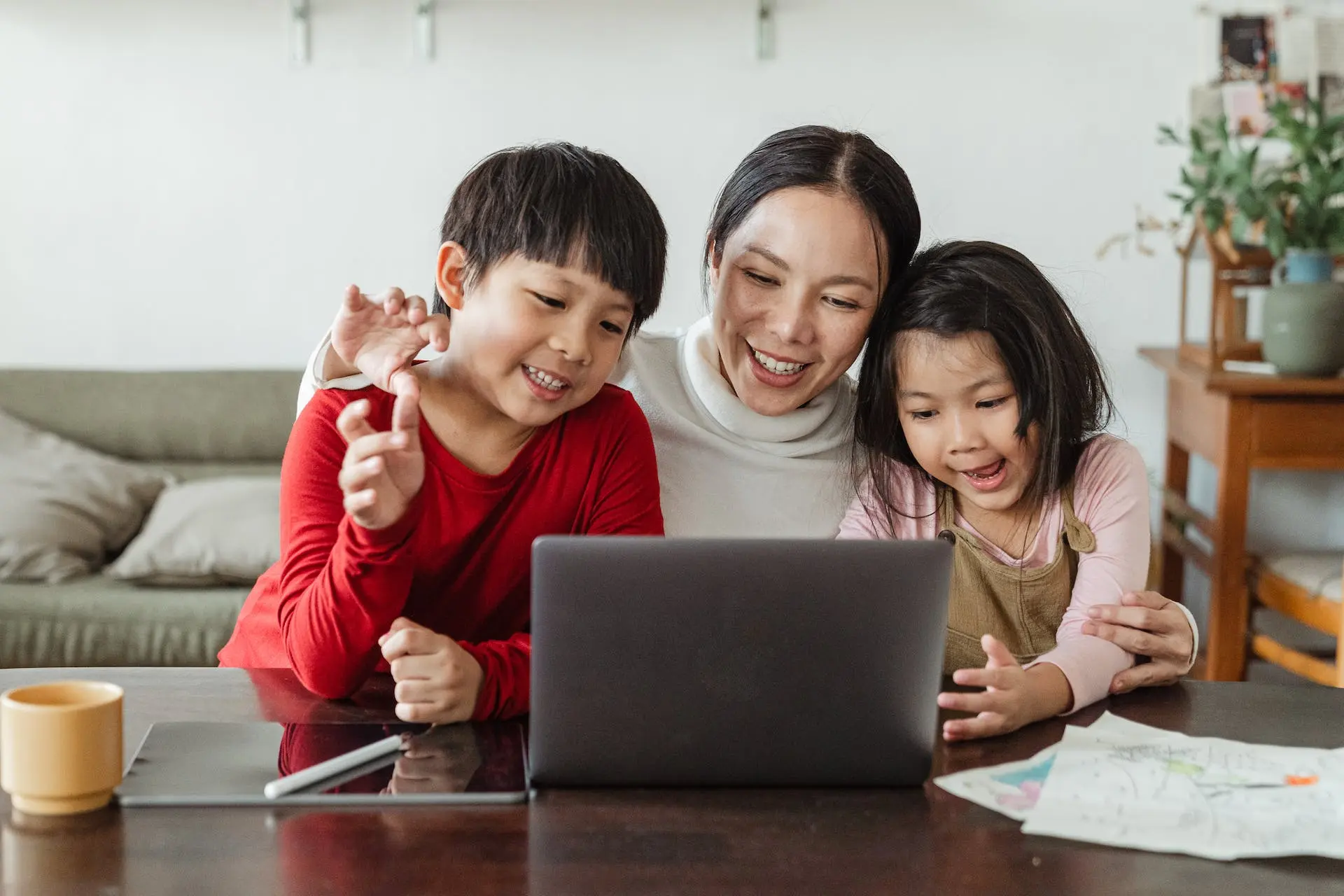 Mother, son, and daughter smiling at laptop